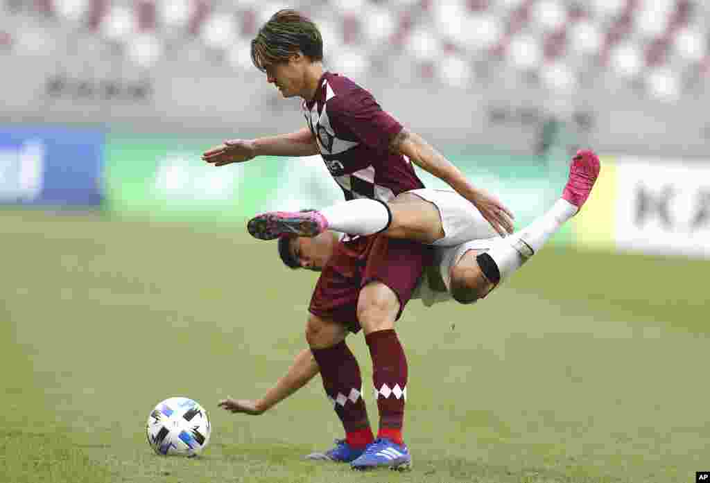Shanghai SIPG's Li Shenglong and Vissel Kobe's Gotoku Sakai, top, fight for the ball during a round of 16 AFC Champions League match in Doha, Qatar.