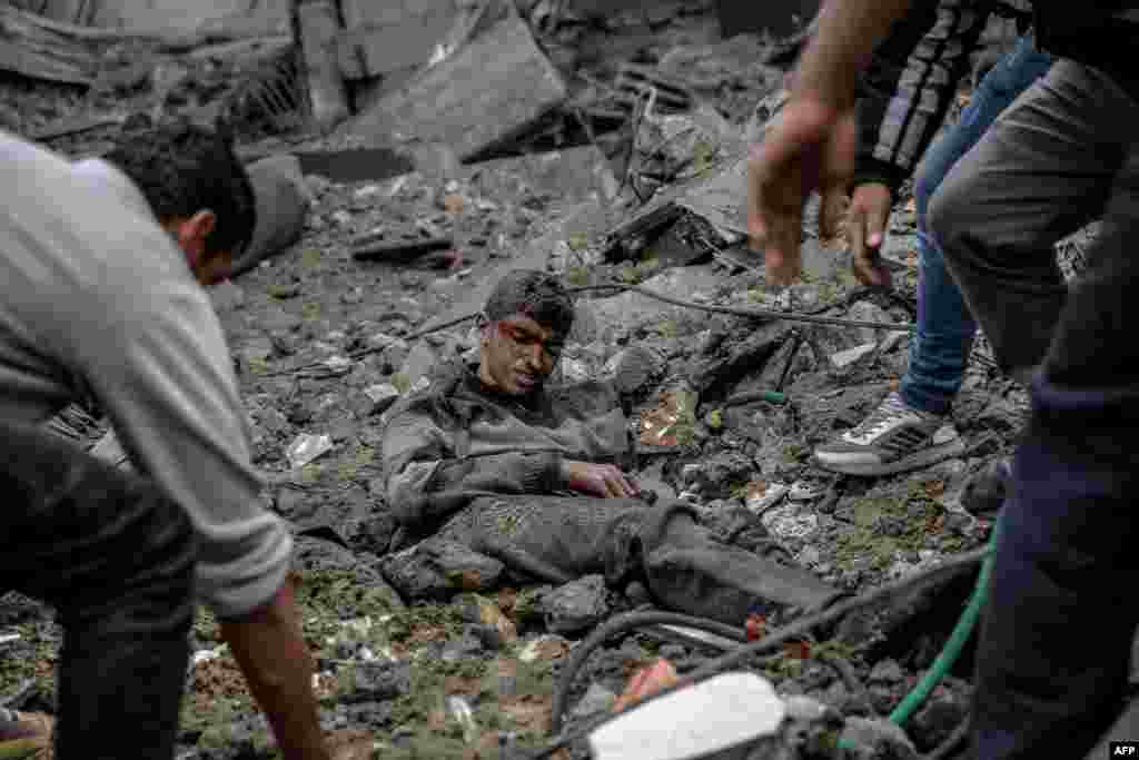 Palestinians rush to rescue a wounded youth after Israeli bombardment in central Gaza City amid the ongoing battles between Israel and the militant group Hamas.