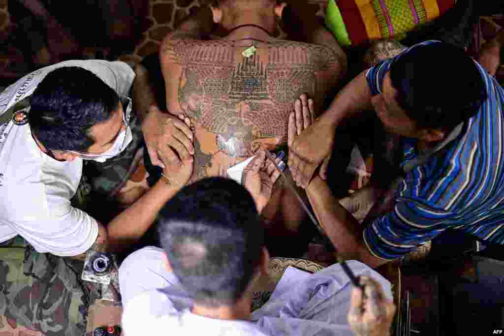 A Buddhist devotee (C) gets a traditional "Sak Yant" tattoo during an annual sacred tattoo festival at the Wat Bang Phra temple in Nakhon Pathom province, Thailand, March 4, 2023.