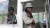 Polisye PNH kanpe nan yon machin lapolis devan bilding kote yo pral nomen Michel Patrick Boisvert nouvo Premye Minis enterime Ayiti nan Potoprens, 25 Avril, 2024. 