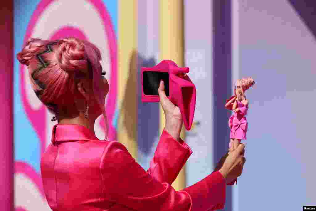 A fan takes a photo of a Barbie doll at the world premiere of the film "Barbie" in Los Angeles, California, July 9, 2023.