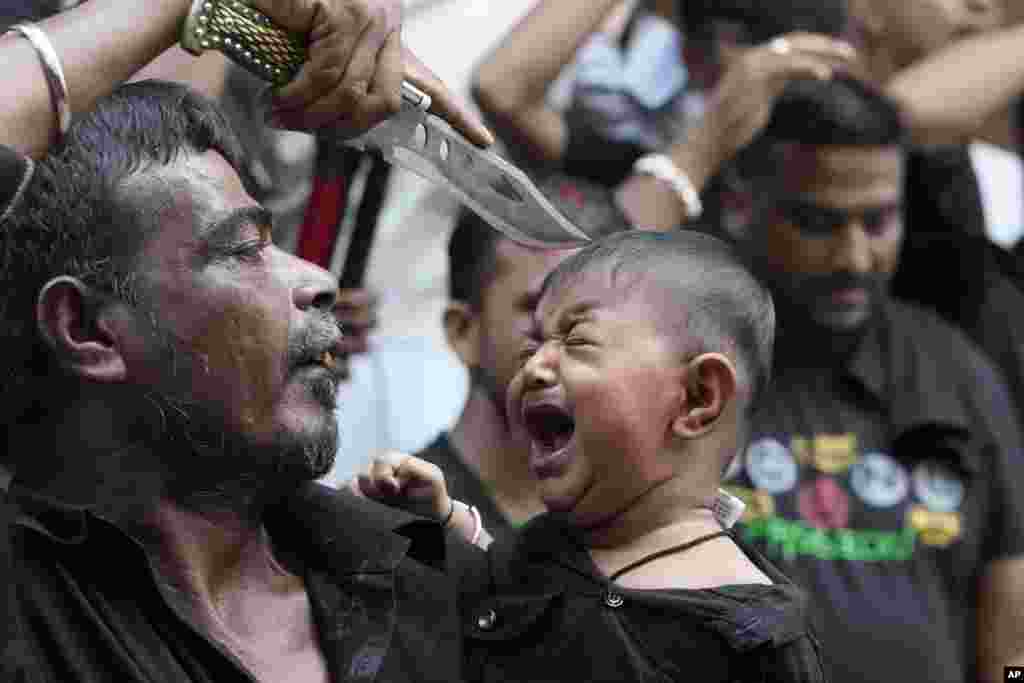 A Shiite Muslim touches the forehead of a child with the point of his knife during a Muharram procession in Ahmedabad, India.
