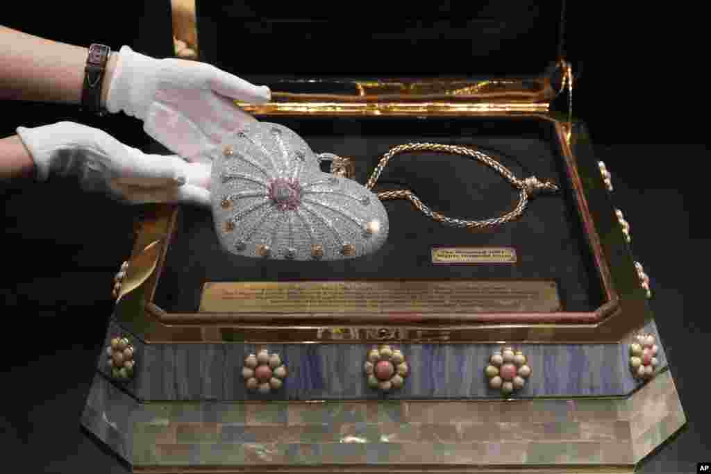 A staff member from the Christie's Hong Kong, displays a heart-shaped handbag, the Mouawad "1001 Nights Diamond Purse" which incorporated 4,517 diamonds with a total weight of 381.92 carats during an auction preview in Hong Kong.