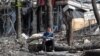 FILE - A man sits in a courtyard near a building damaged during the Ukraine-Russia conflict in the southern port city of Mariupol, Ukraine, April 25, 2022.