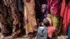FILE - A woman holds her child as she waits for high-nutrition foods and medical consultations at Tawkal 2 Dinsoor camp for internally displaced persons in Baidoa, Somalia, Feb. 14, 2022. 