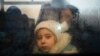 FILE - A girl fleeing the conflict in Ukraine looks on from inside of a bus heading to the Moldovan capital Chisinau, after crossing the Moldova-Ukraine border checkpoint near the town of Palanca, March 2, 2022.