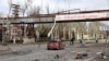 Фото: місцеві мешканці Маріуполя на тлі частково зруйнованого заворду "Іллічсталь", 16 квітня 2022 року