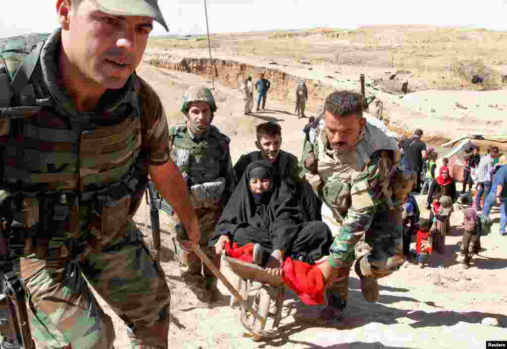 Kurdish Peshmerga forces help people, who fled from their homes in Hawija, as they arrive to be transported to camps for displaced people, in southwest of Kirkuk, Iraq, Oct. 4, 2017.