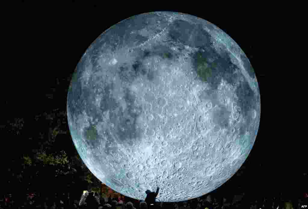 A child is touching a light object called "The Museum of the Moon" created by British artist Luke Jerram and displayed at the Medical Garden in Bratislava, Oct. 7, 2017, during the White Night festival.