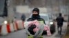 FILE - A firefighter holds the baby of a refugee fleeing the conflict from neighboring Ukraine at the Romanian-Ukrainian border, in Siret, Romania, March 7, 2022.