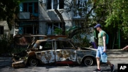 A man carries water in front of an apartment building damaged in an overnight missile strike, in Sloviansk, Ukraine, May 31, 2022.