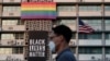 Un hombre camina frente a una pancarta de Black Lives Matter y de una bandera de arcoíris en la embajada de Estados Unidos en Corea del Sur, el domingo 14 de junio de 2020. 