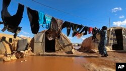 FILE - A woman hangs laundry in a flooded refugee camp in Idlib province, Syria, Dec. 21, 2021.