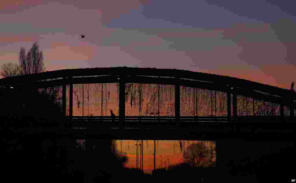 A man runs along a bridge at sunset, at the "Parco Nord" North Park in Milan, Italy,