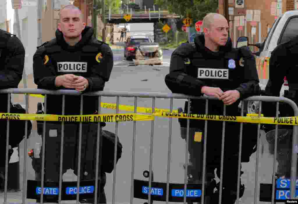 Virginia State police stand guard at the crime scene where a vehicle plowed into a crowd of counter protesters and two other vehicles (rear) near the "Unite the Right" rally organized by white nationalists in Charlottesville, Aug. 12, 2017.