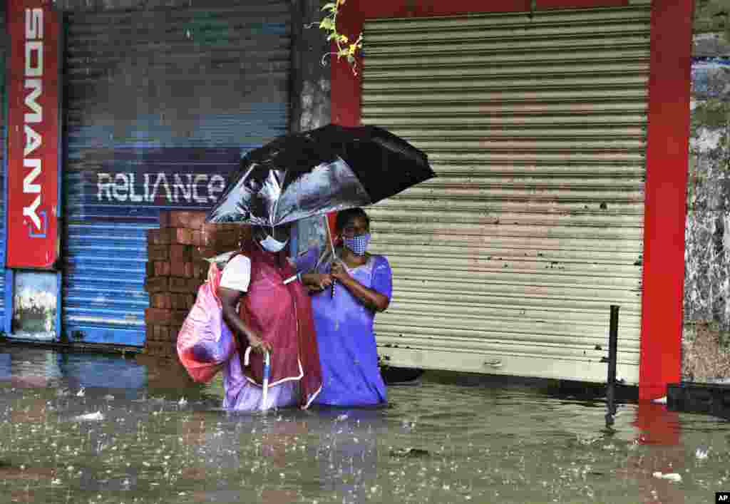 People make their way through a water logged street during heavy rain in Mumbai, India.
