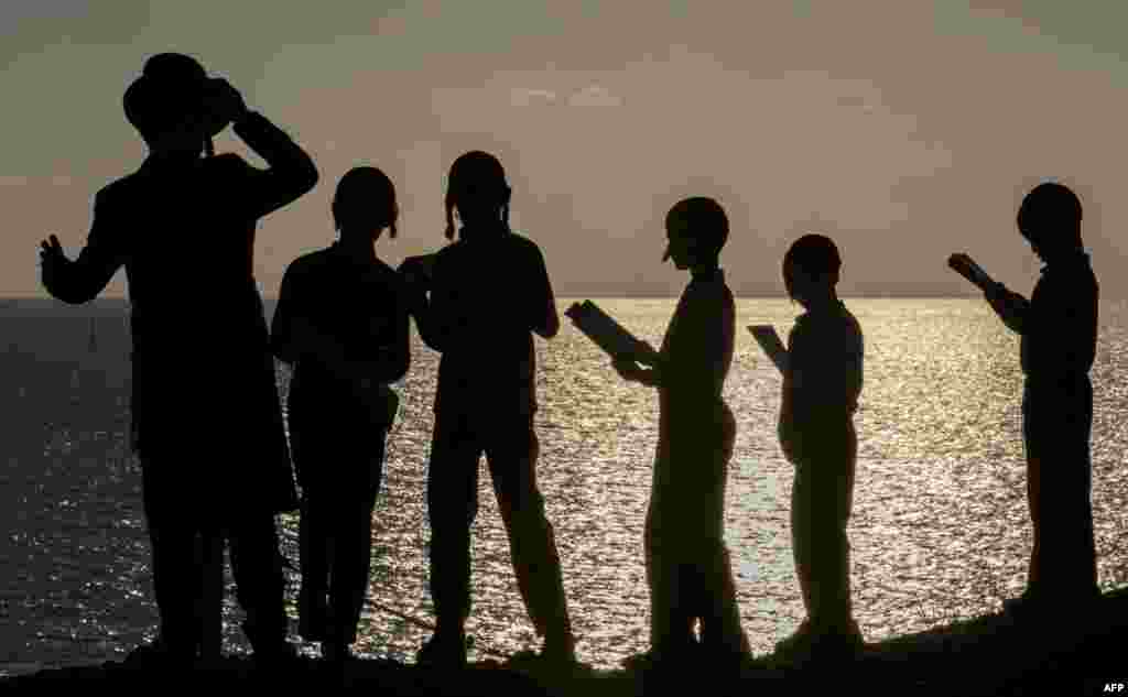 Ultra-Orthodox Jewish boys pray along the Mediterranean Sea in the Israeli city of Herzliya, near Tel Aviv, while performing the "Tashlich" ritual during which "sins are cast into the water to the fish".