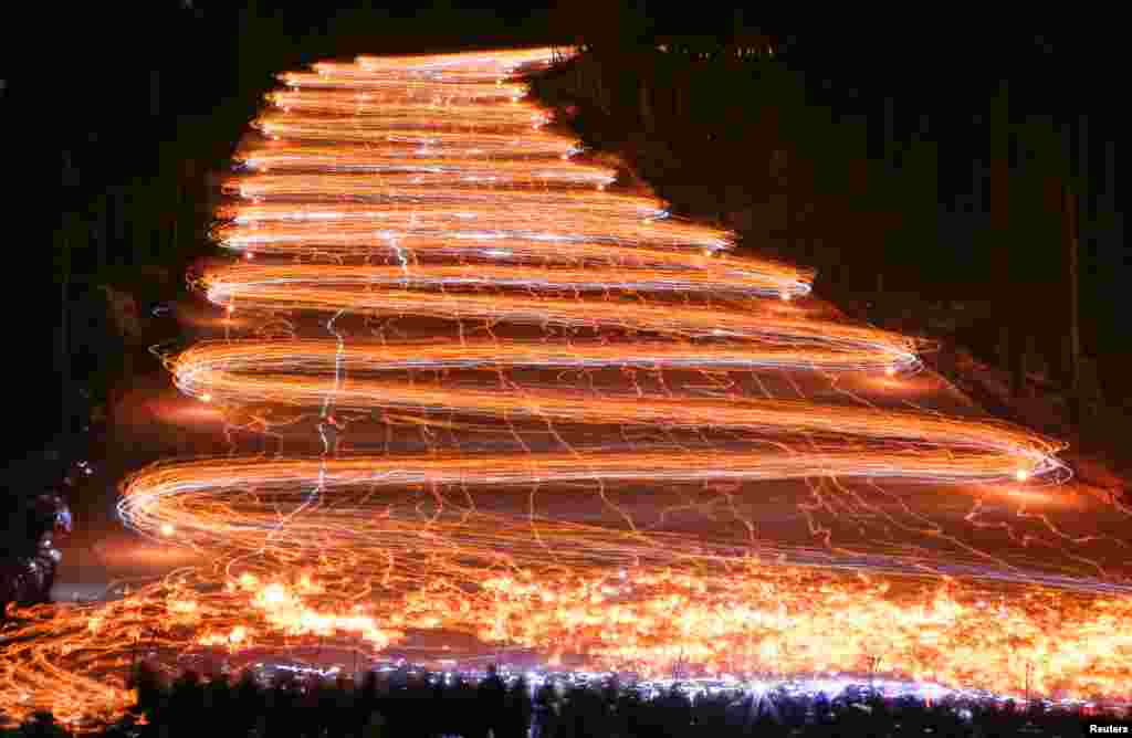 Hundreds of skiers and snowboarders descend from a slope while holding lit torches and flashlights in the Siberian town of Zheleznogorsk, northeast of Krasnoyarsk, Russia, Feb. 26, 2017.