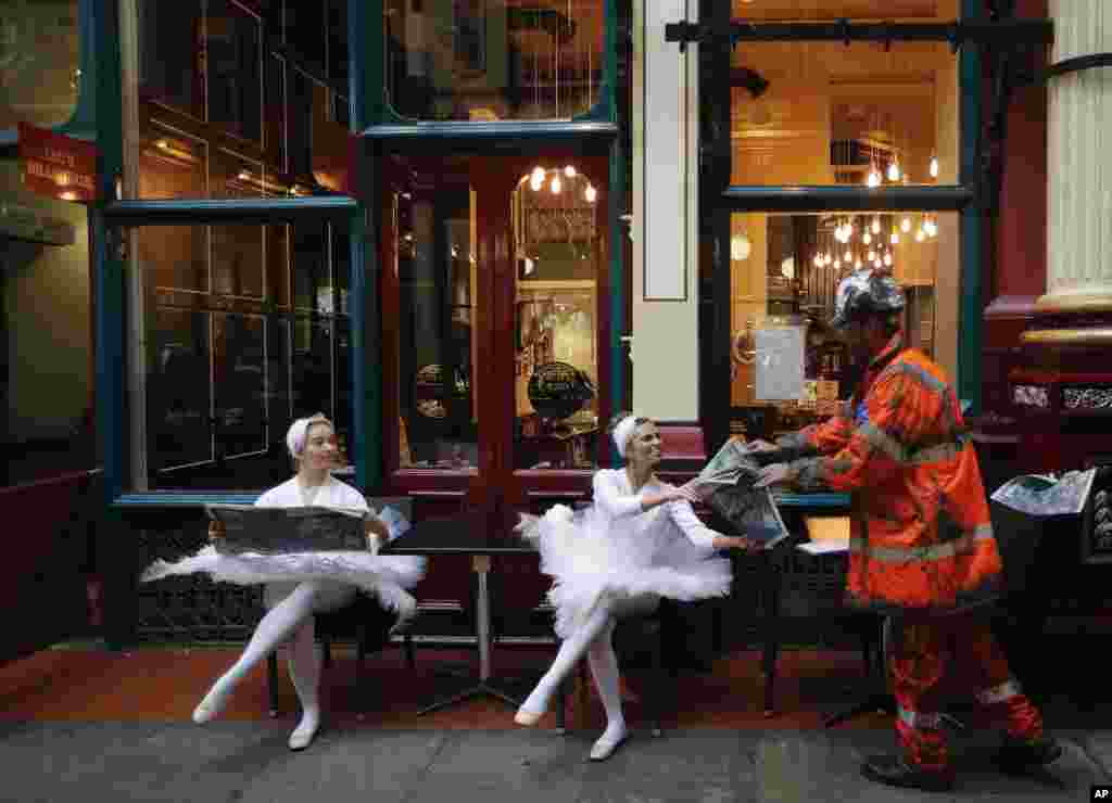 Actors sit in the streets of Leadenhall Market in London. A Large-scale artwork was unveiled accompanied by characters to tell the story of London's world-famous insurance market in a three day-campaign that aims to explain how insurers and brokers support people, businesses, charities and governments all round the world.