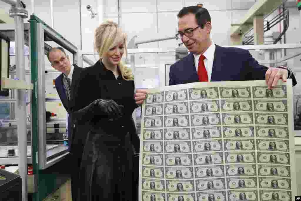 Treasury Secretary Steven Mnuchin shows his wife Louise Linton a sheet of new $1 bills, the first currency notes bearing his and U.S. Treasurer Jovita Carranza's signatures, at the Bureau of Engraving and Printing (BEP) in Washington, D.C., No. 15, 2017.