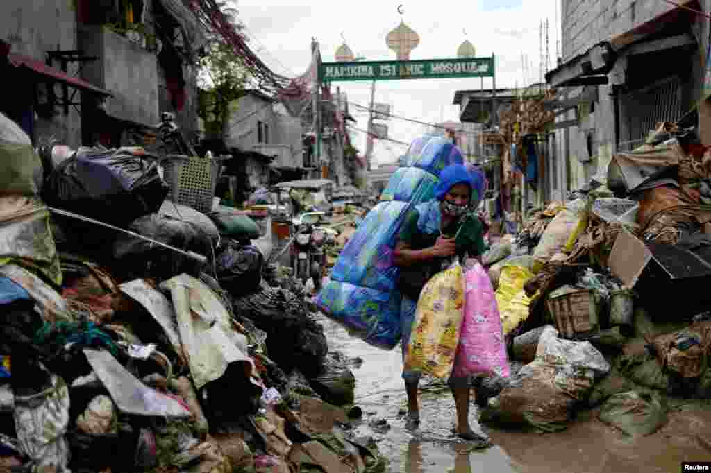 A man selling pillows and mattresses walks past debris from the flood brought by Typhoon Vamco, in Marikina, Metro Manila, Philippines.