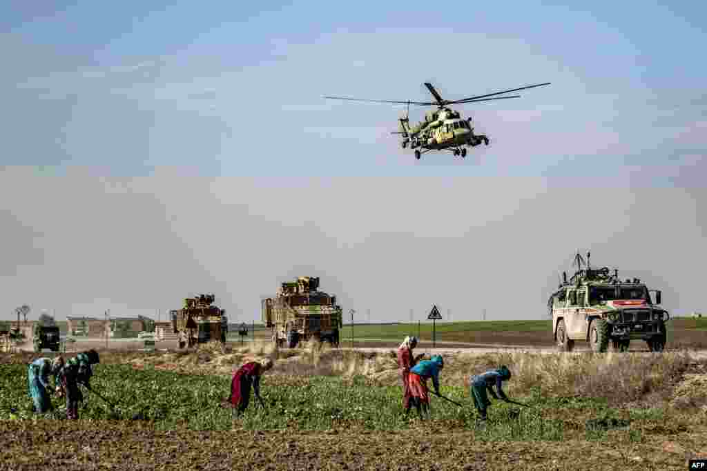 A Russian Mil Mi-17 military helicopter flies over a joint Russian-Turkish military patrol convoy in the countryside near Darbasiyah along the border with Turkey in Syria's northeastern Hasakah province.