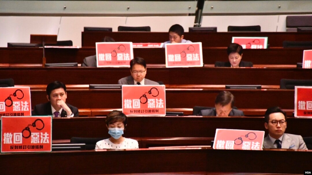 多名民主派立法會議員在座位前擺放示威標語，要求港府撤回《逃犯條例》修訂。（美國之音湯惠芸攝）