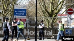 Police officers and building workers are seen outside St Thomas' Hospital in London after British Prime Minister Boris Johnson was admitted with persistent coronavirus (COVID-19) symptoms, London, April 6, 2020. 