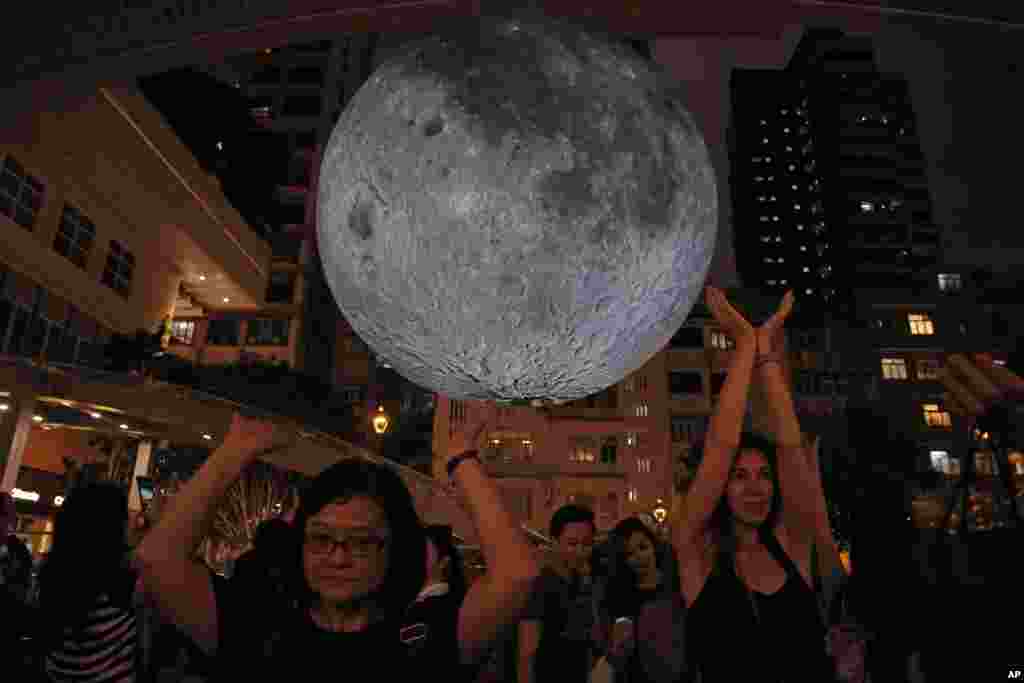 Visitors pose for photographs in front of an installation "Museum of the Moon", a giant seven-meter-wide glowing sculpture of the moon, created by British artist Luke Jerram in Hong Kong to celebrate the Mid-Autumn Festival.