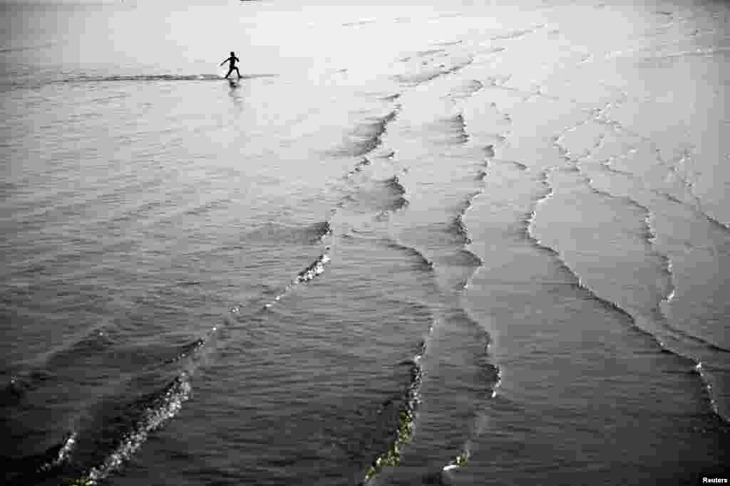 A boy runs in shallow water on a beach in the coastal city of Larnaca, Cyprus, Nov. 12, 2017.
