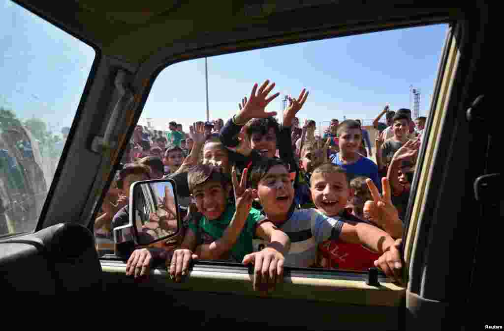 Iraqi boys gather to welcome security forces members, who continue to advance in military vehicles in Kirkuk, Iraq.