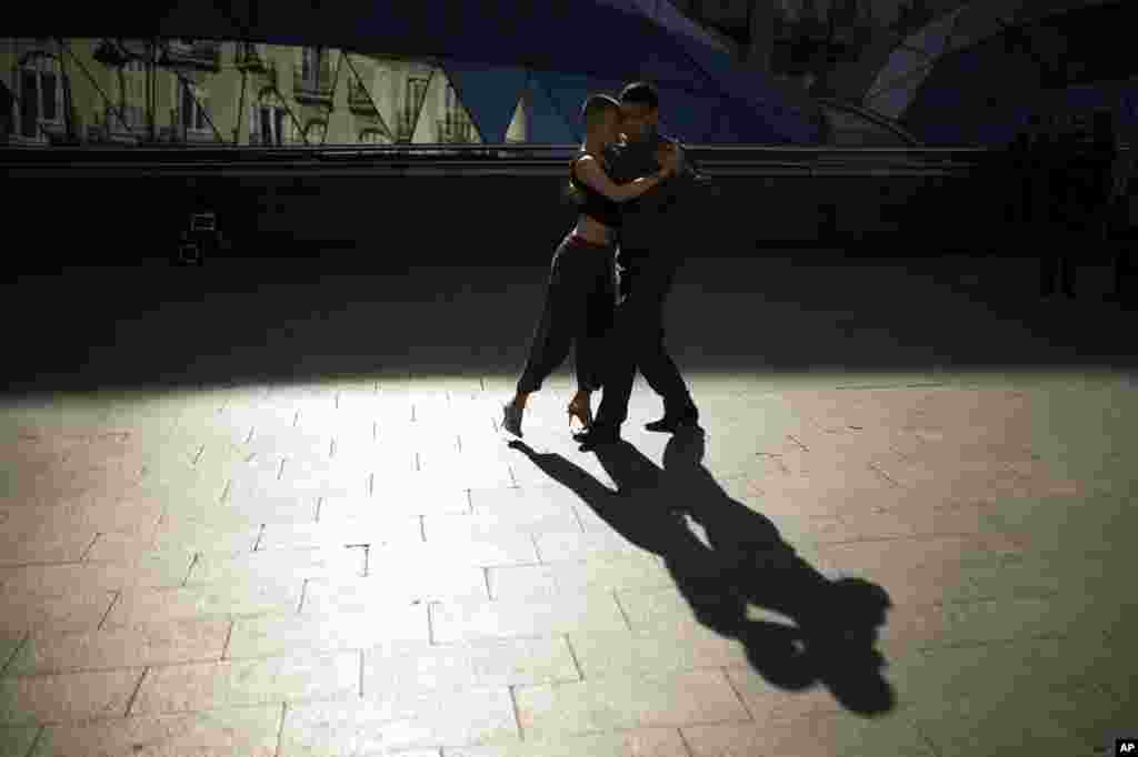 An Argentinian couple cast their shadow on the ground as they dance the tango for money at Sol square in downtown Madrid, Spain.