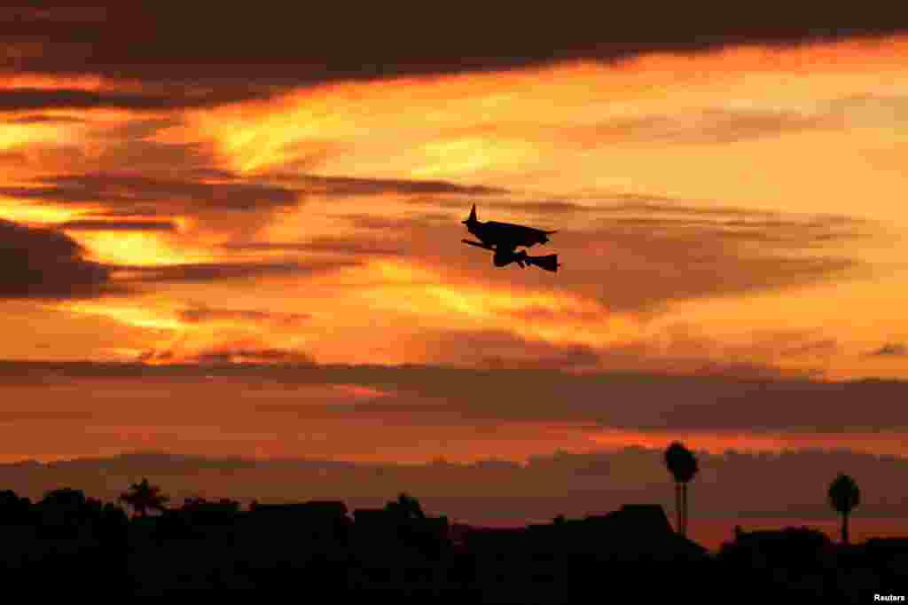 A remote-controlled witch on a broom flies over a Southern California neighborhood after sunset on Halloween night in Encinitas, California, Oct. 31, 2017.