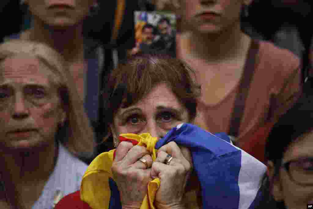 A protester holding a Catalan flag reacts as she takes part in a rally outside the Catalan Parliament, in Barcelona, Spain.