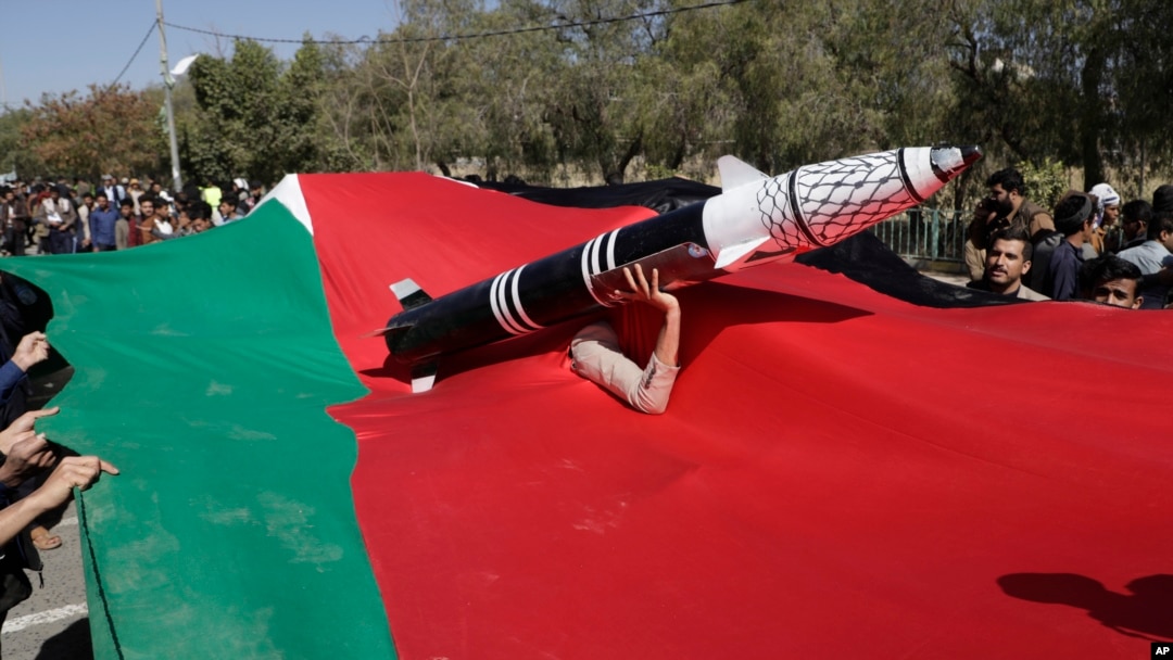 A Houthi supporter carries a mock rocket as he peers from a Palestinian flag during a protest in Sanaa, Yemen, on Jan. 22, 2025.