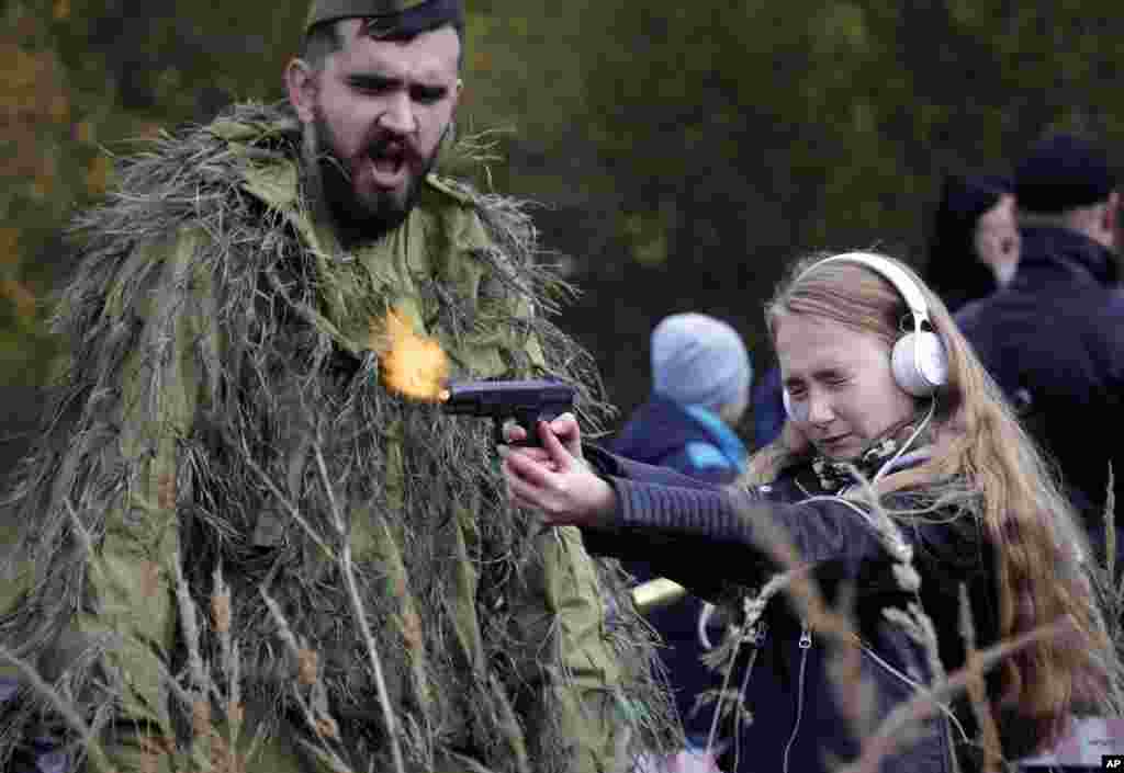 A girl shoots a gun at an weapon exhibition during a military show in St.Petersburg, Russia, Oct. 14, 2017.