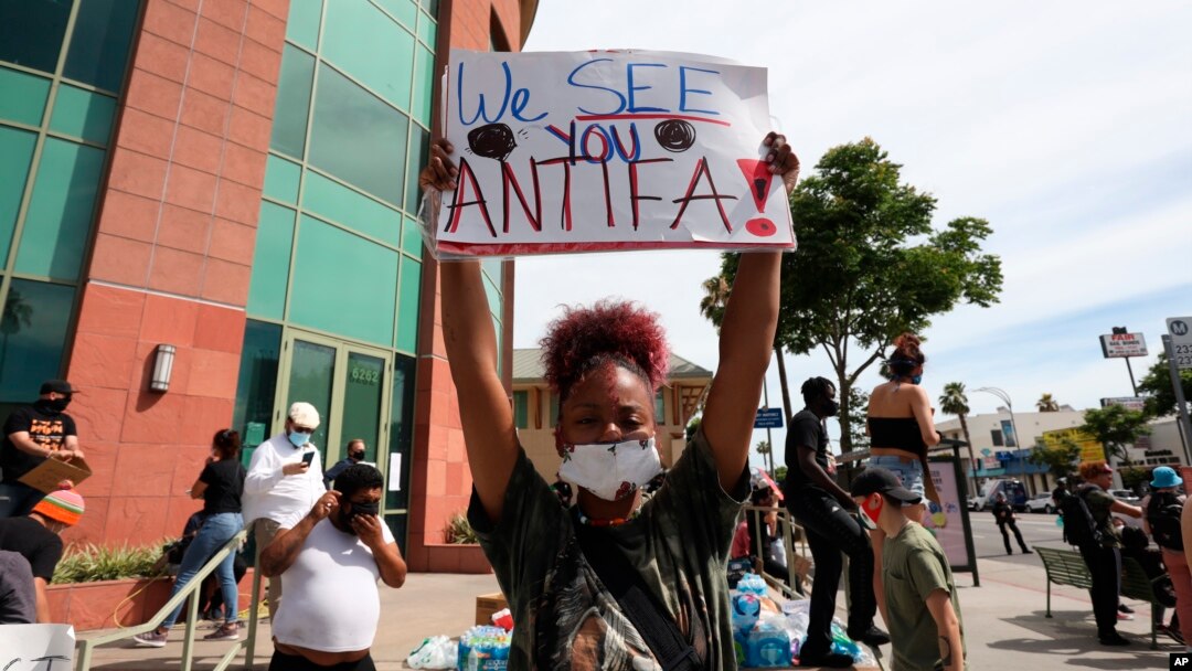 A woman holds a sign addressing antifa at a protest in Los Angeles on June 1, 2020, over the death of George Floyd, who died May 25 in Minneapolis. 
