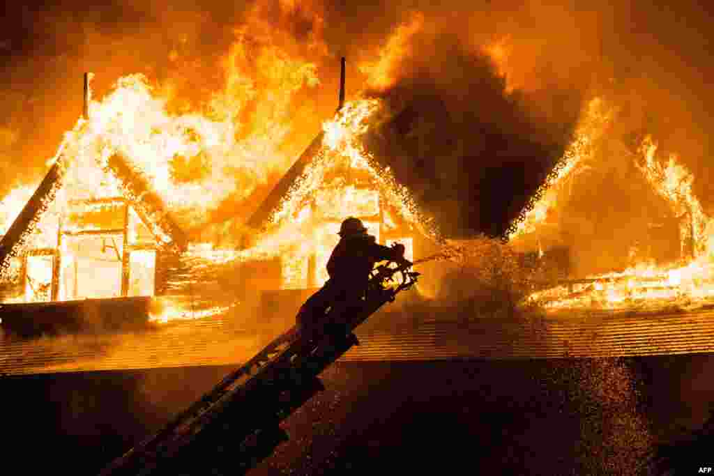 A firefighter extinguishes a fire at Kandawgyi Palace hotel in Yangon, Myanmar. One person died in a pre-dawn blaze that tore through a teakwood hotel popular with foreign visitors to the country's main city.