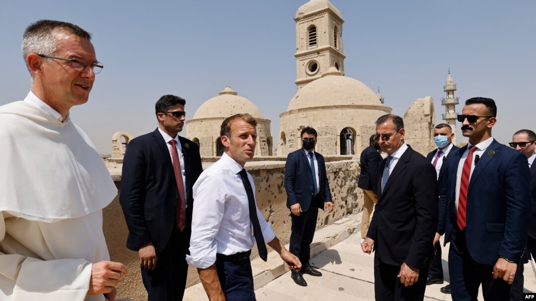 French President Emmanuel Macron (C) tours the Our Lady of the Hour Church with Dominican Father Olivier Poquillon (L) in Iraq's second city of Mosul, in the northern Nineveh province, on August 29, 2021. 