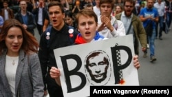 A protester carries a poster reading "Thief" and depicting Russian President Vladimir Putin during a rally against planned increases to the nationwide pension age in St. Petersburg, Russia September 9, 2018. REUTERS/Anton Vaganov