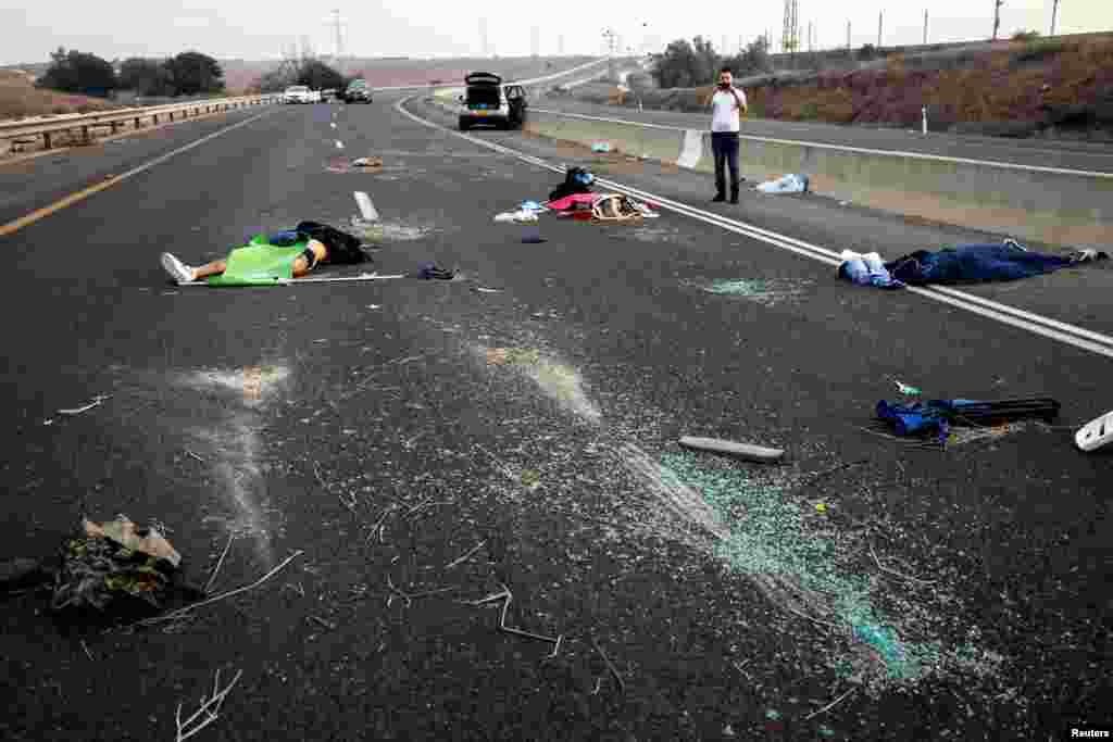 A man takes a photo of dead people strewn across a road following a mass-infiltration by Hamas gunmen from the Gaza Strip, in the Sderot area, southern Israel, Oct. 7, 2023.