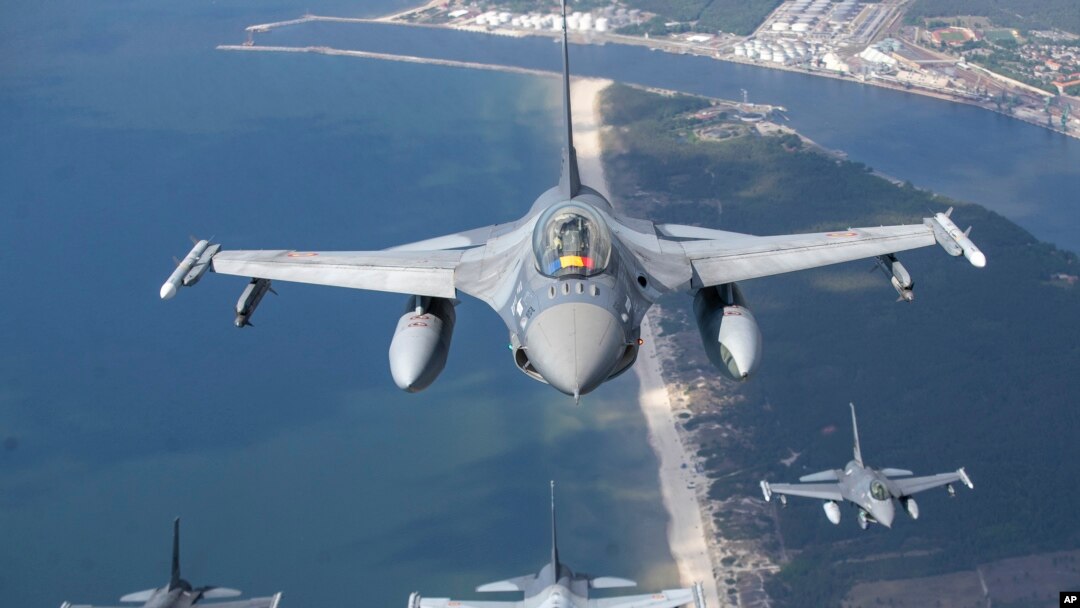 A Romanian Air Force F- 16s military fighter jet, in front, and a Portuguese Air Force F- 16s military fighter jets participating in NATO's Baltic Air Policing Mission operate over the Baltic Sea, Lithuanian airspace, Monday, May 22, 2023. (AP Photo/Mindaugas Kulbis)