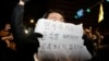 2024年12月4日，韩国总统尹锡烈宣布戒严后，人们聚集在首尔国会大厦，一个人举着一块写着“民主不会向尹锡烈屈服”字样的标语牌。