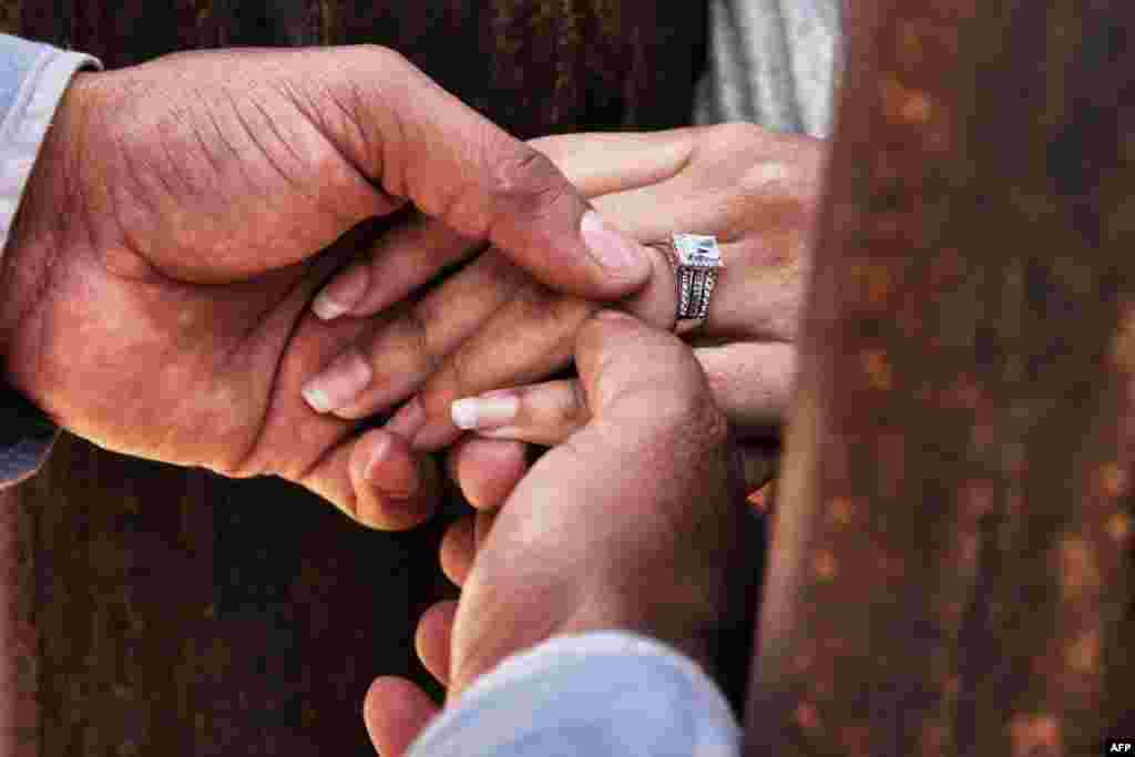 Rogelio puts a wedding ring on Miriam's finger as they get married through the border wall between Mexico and the United States, during the "Keep our dream alive" event, in Ciudad Juarez, Chihuahua state, Mexico, Dec. 10, 2017.