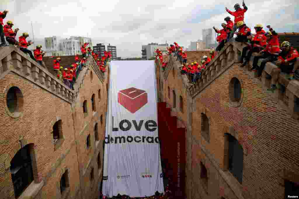 Firemen react as they hang a huge banner in favor of the banned October 1 independence referendum at the Catalonia's History Museum in Barcelona, Spain.