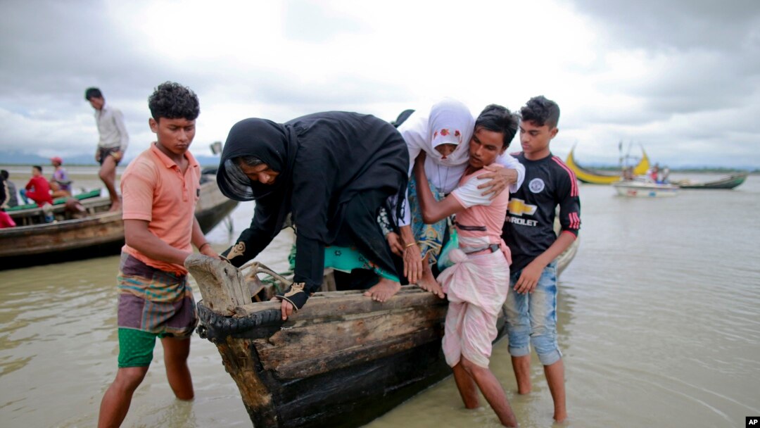 Bangladeshi villagers help two elderly Rohingya women from a boat after crossing a canal at Shah Porir Deep, in Teknak, Bangladesh, Aug. 31, 2017.