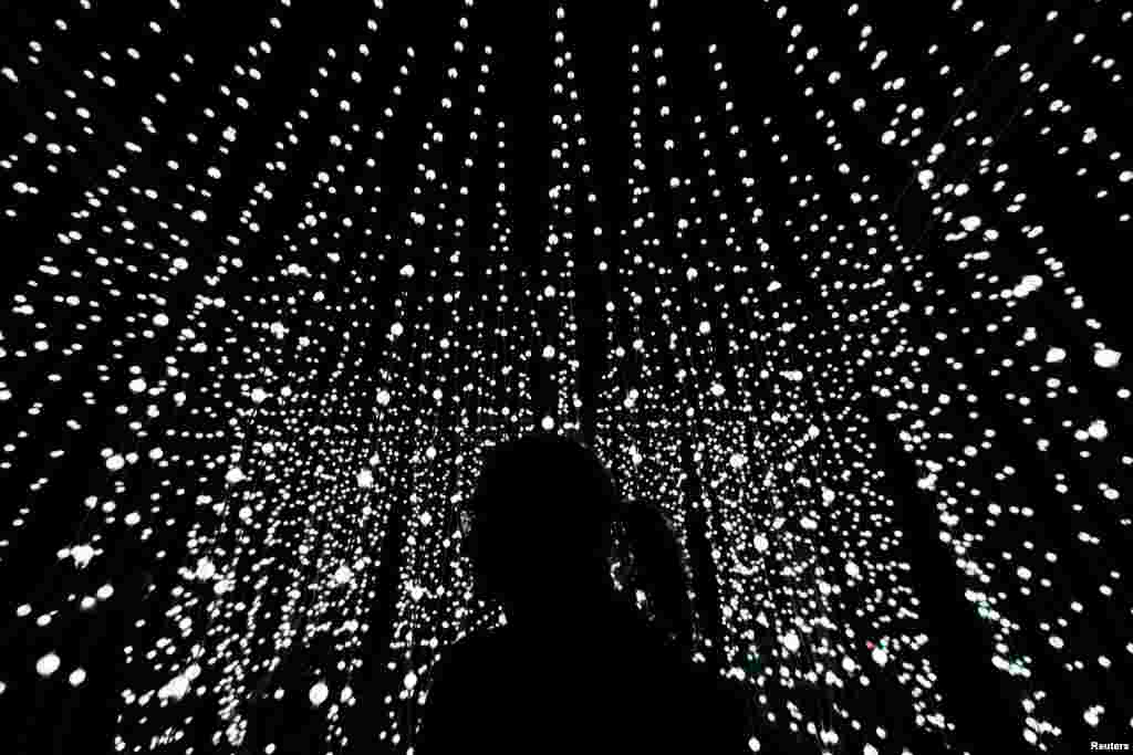 A woman stands in front of an installation during a light festival in Prague, Czech Republic.