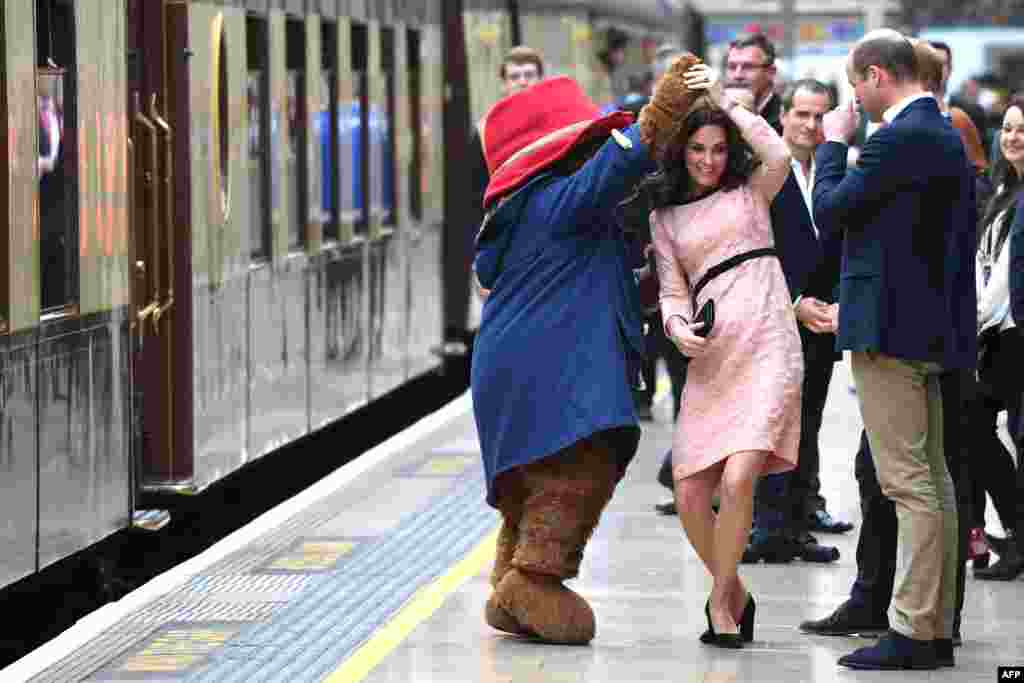 Britain's Catherine, Duchess of Cambridge, (C) dances with a person in a Paddington Bear outfit by her husband Britain's Prince William, Duke of Cambridge, as they attend a charities forum event at Paddington train station in London.