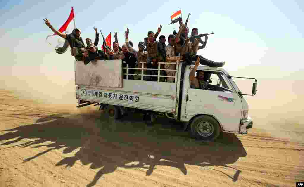 Fighters of the Hashed al-Shaabi paramilitaries flash the victory gesture while riding in the back of a truck advancing towards the northern Iraqi town of Sharqat.