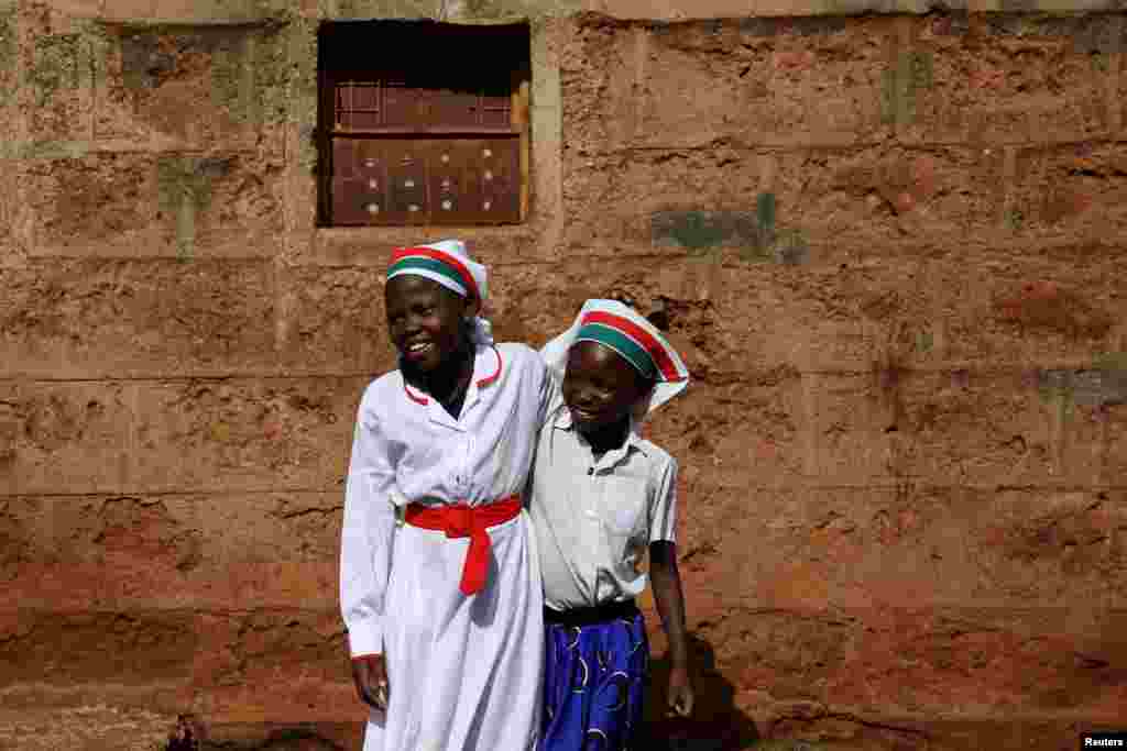 Girls smile at the beginning of a Sunday service outside of an African Divine Church near the slum area of Korogocho in the capital Nairobi, Kenya.